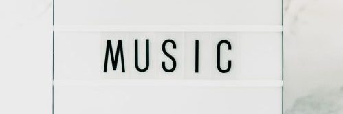 A minimalist light box displaying the word 'MUSIC' on a white background.