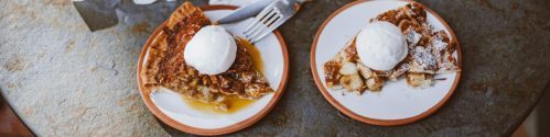A mouthwatering apple pie with ice cream serving alongside tea on a cozy table setup.